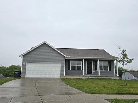 A grey house with a black door and a white garage door.